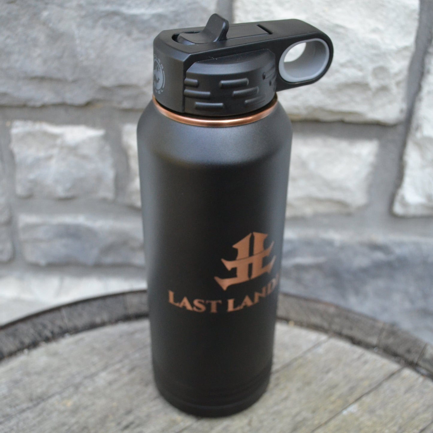 Black water bottle with a logo on a stone surface