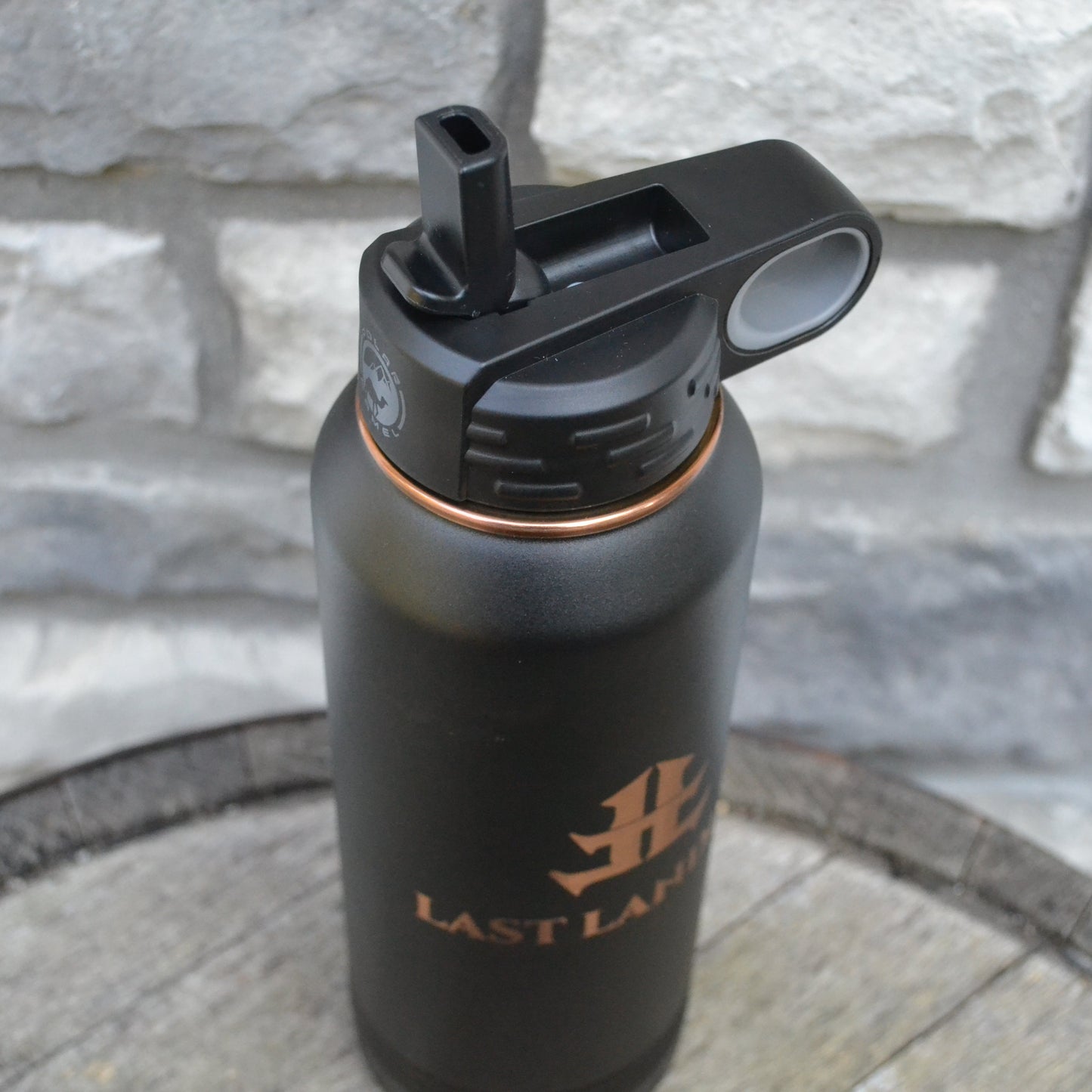 Black water bottle with a logo on a stone surface