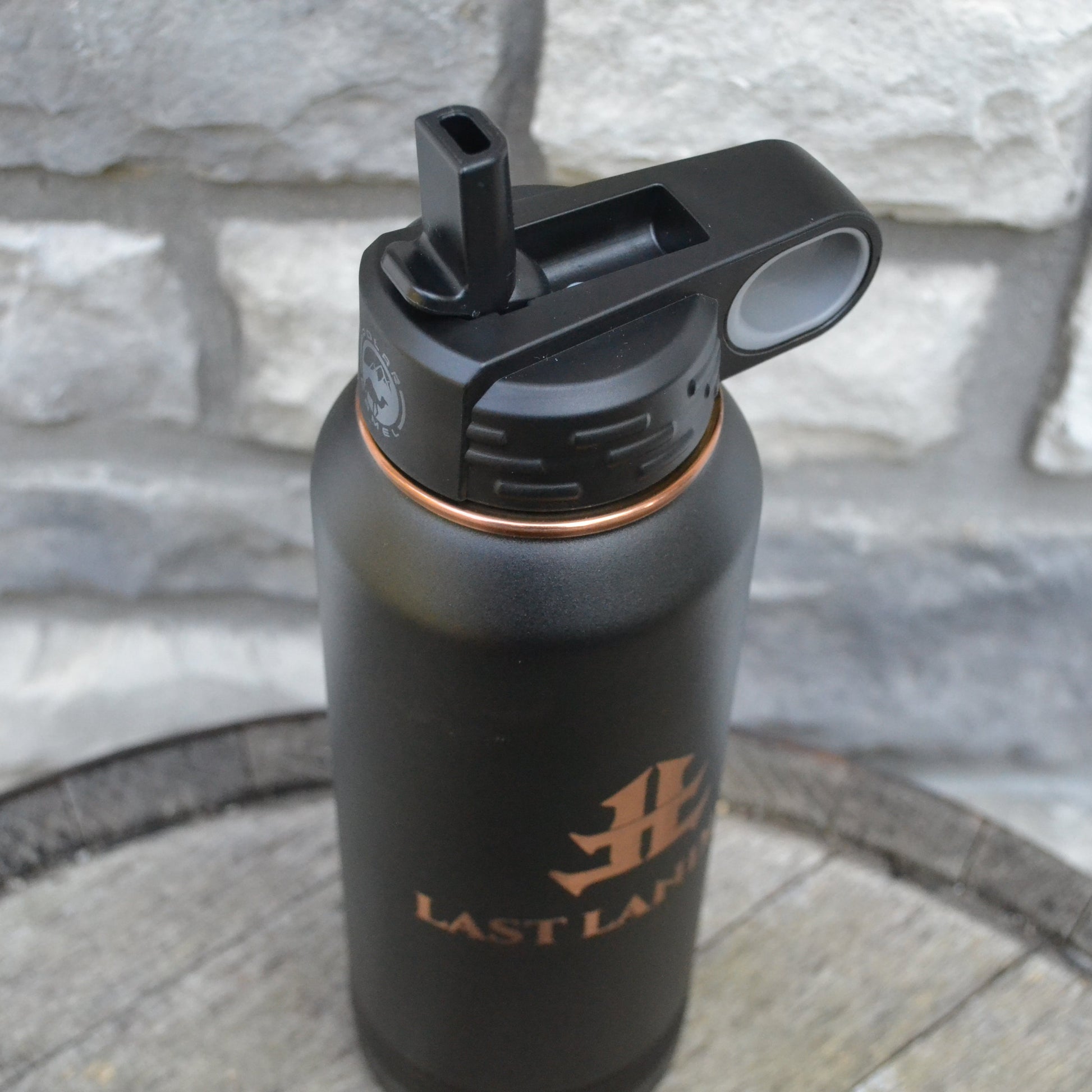 Black water bottle with a logo on a stone surface