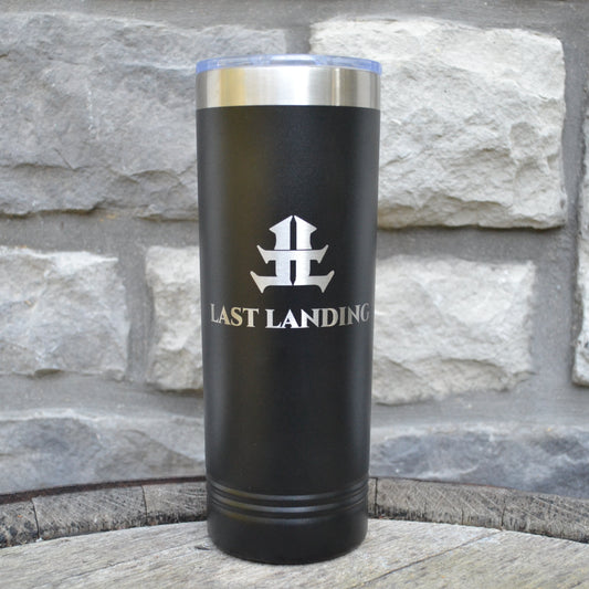 Black tumbler with 'Last Landing' logo on a stone surface