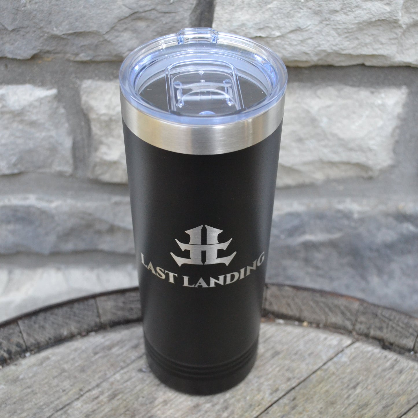 Black tumbler with silver lid on a stone surface