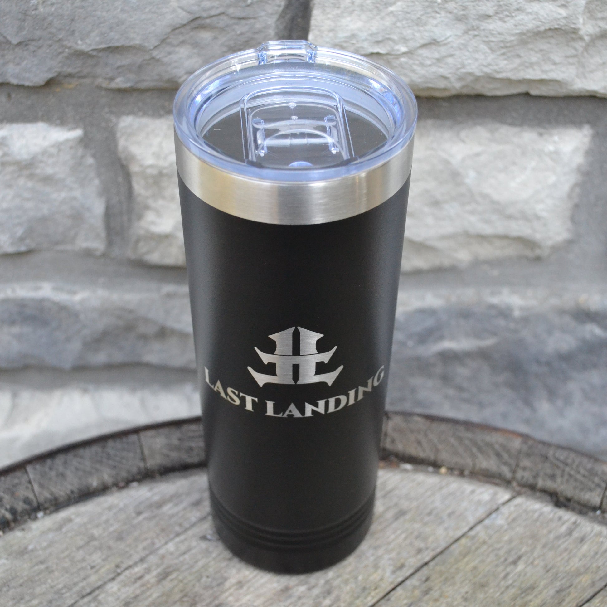 Black tumbler with silver lid on a stone surface